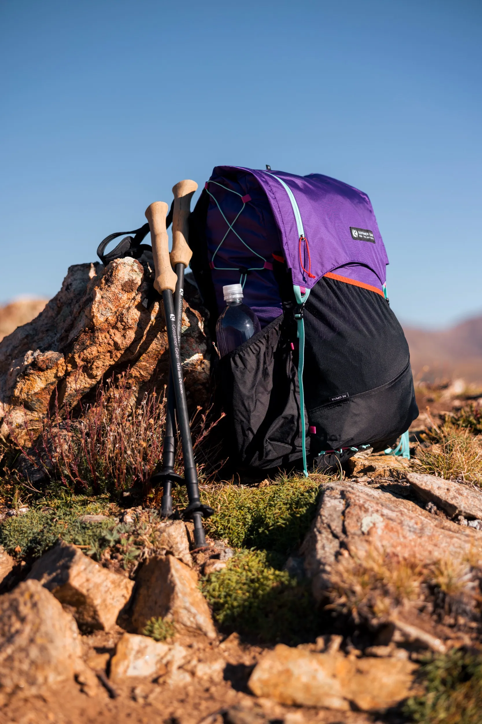 Purple Gossamer Gear pack and trekking poles leaning on a rock outcrop