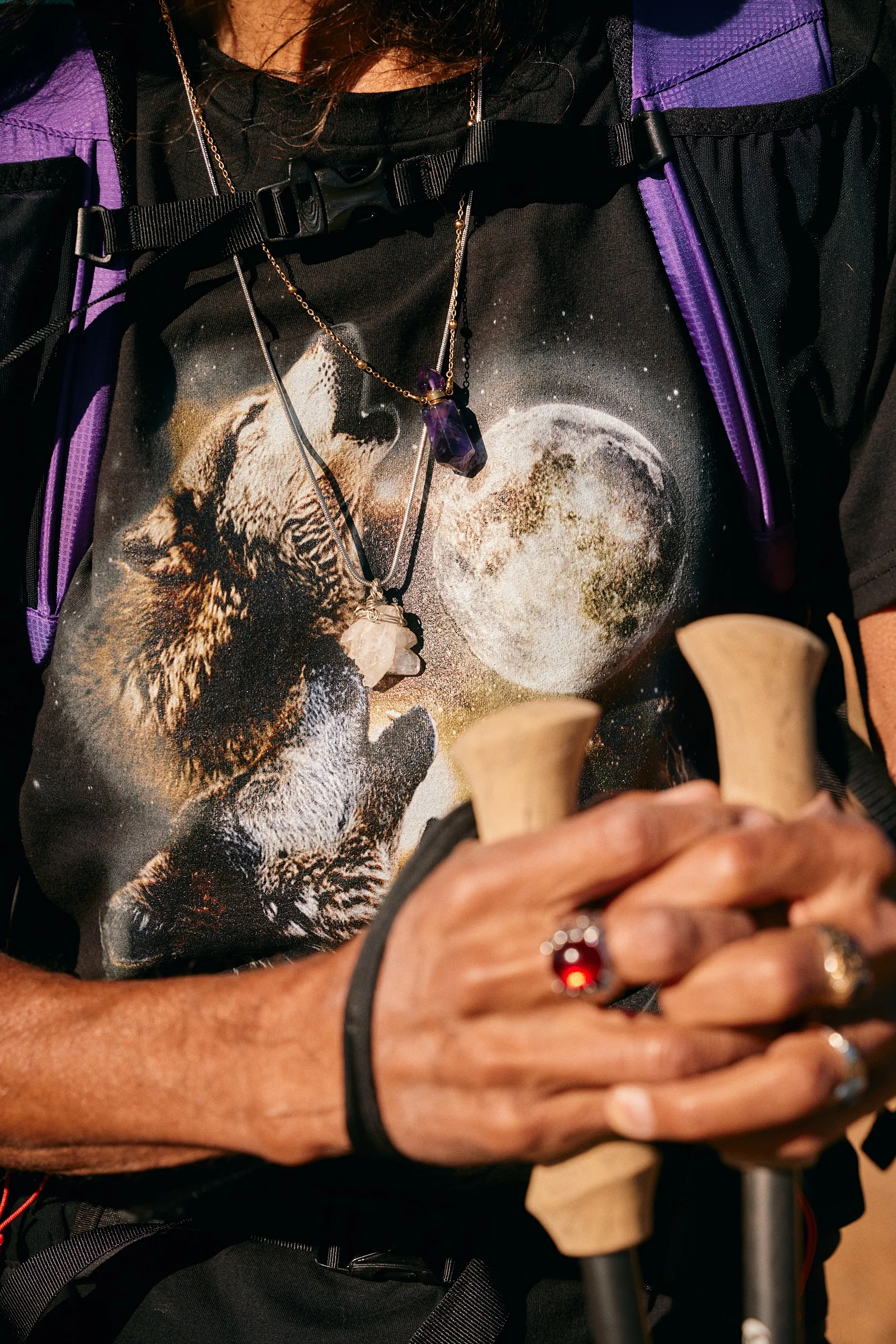 Close-up of hands with rings on cork trekking pole grips over a graphic tee